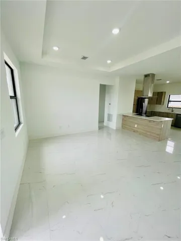 Unfurnished living room with baseboards, a tray ceiling, and visible vents