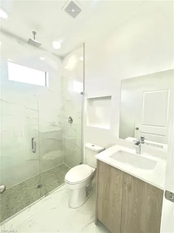 Full bathroom with visible vents, vanity, marble finish floor, toilet, and a marble finish shower