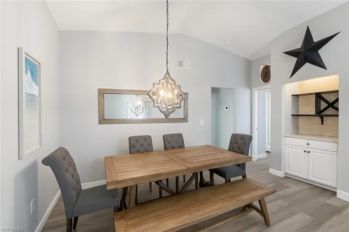 Dining space with light wood finished floors, a chandelier, and high vaulted ceiling