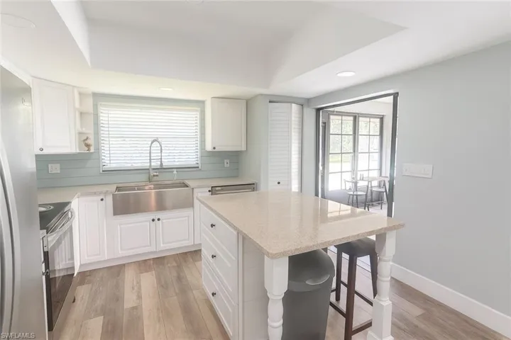 Kitchen with open shelves, light wood finished floors, white cabinets, stainless steel appliances, and a kitchen island