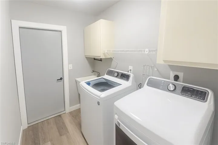 Washroom featuring cabinet space, light wood-style flooring, and separate washer and dryer