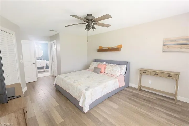 Bedroom featuring light wood-style floors, ensuite bath, a closet, and ceiling fan
