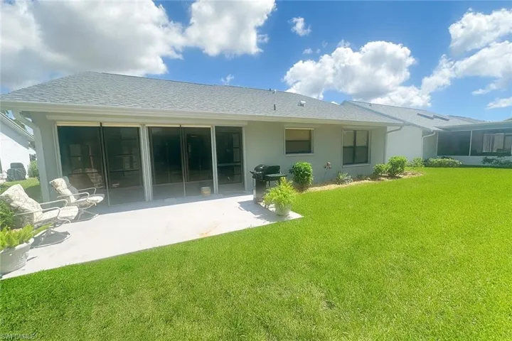 Back of property with a lawn, a shingled roof, a patio, and stucco siding