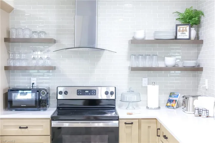 Kitchen features sleek countertops, state-of-the-art appliances, and ample cabinetry, along with open floating shelves.
