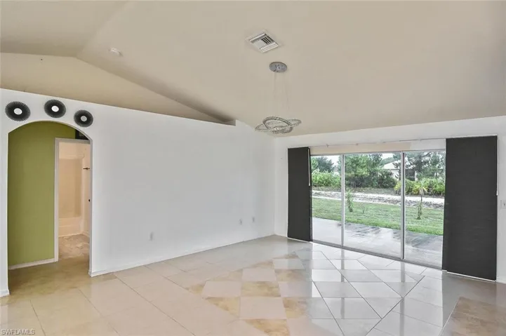 Tiled empty room featuring lofted ceiling