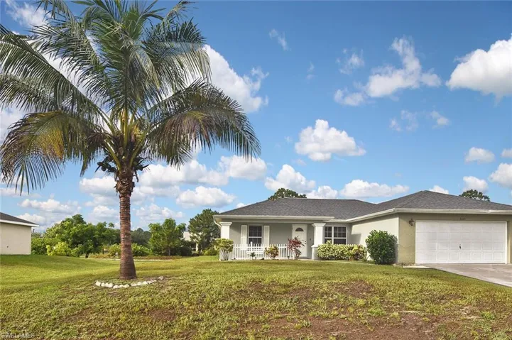 View of front of home with a garage, a front lawn, and covered porch