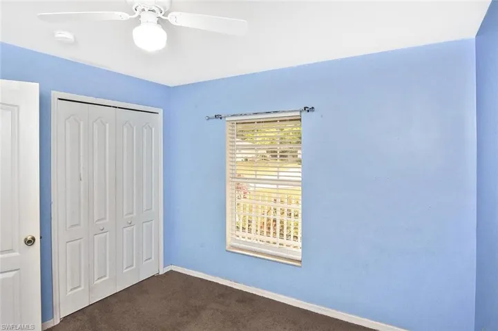 Unfurnished bedroom featuring a closet, dark colored carpet, and ceiling fan