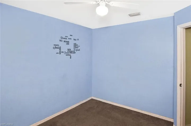 Empty room with ceiling fan and dark carpet