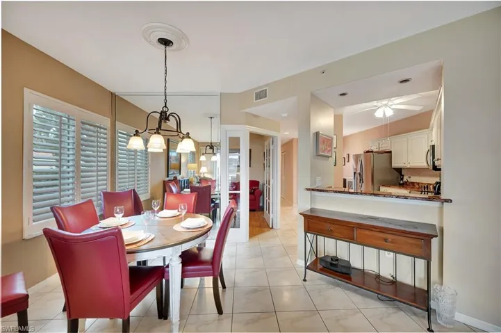 Tiled dining area featuring ceiling fan with notable chandelier