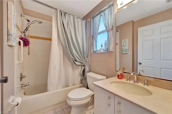 Full bathroom featuring shower / bath combination with curtain, vanity, tile patterned flooring, and toilet