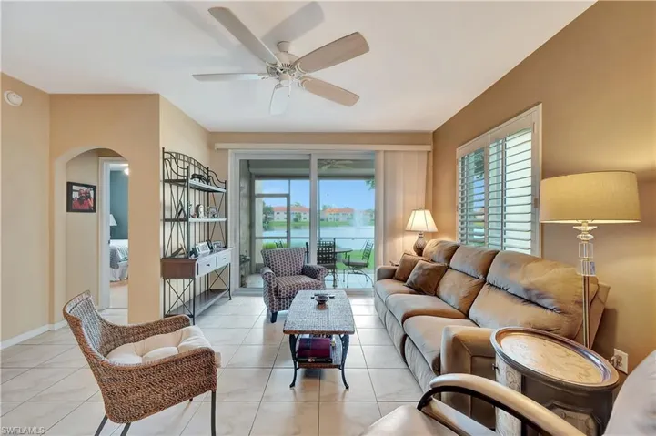Tiled living room with a wealth of natural light, a water view, and ceiling fan
