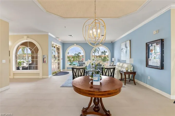 Dining room featuring light tile patterned floors, plenty of natural light, ornamental molding, and a chandelier