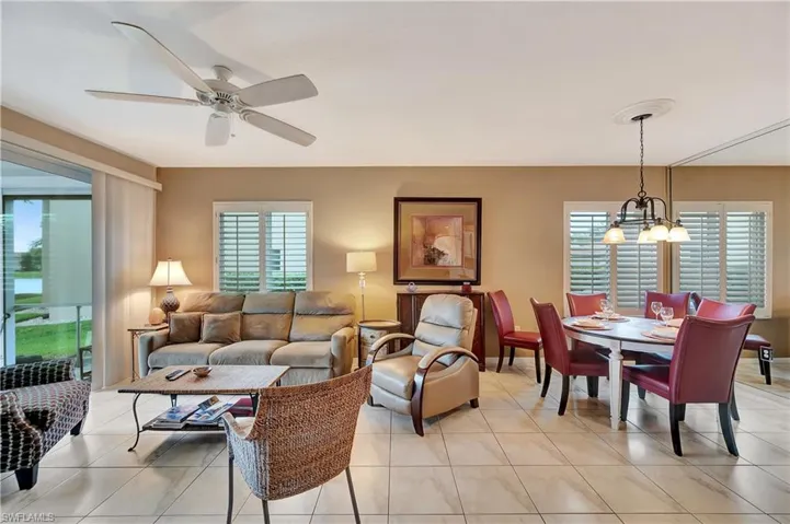 Tiled living room with ceiling fan with notable chandelier