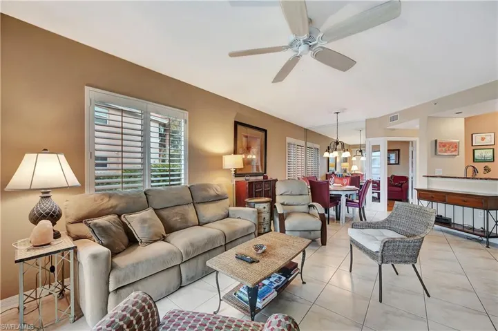 Living room with ceiling fan with notable chandelier and light tile patterned floors