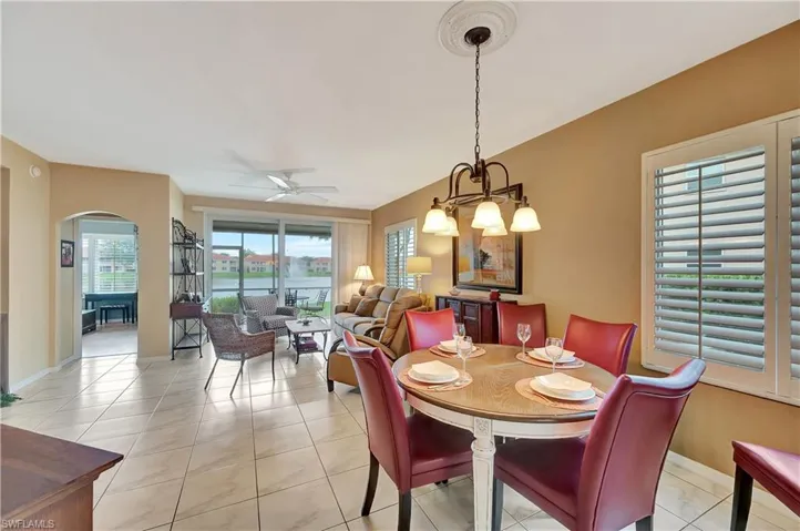 Tiled dining room with ceiling fan with notable chandelier
