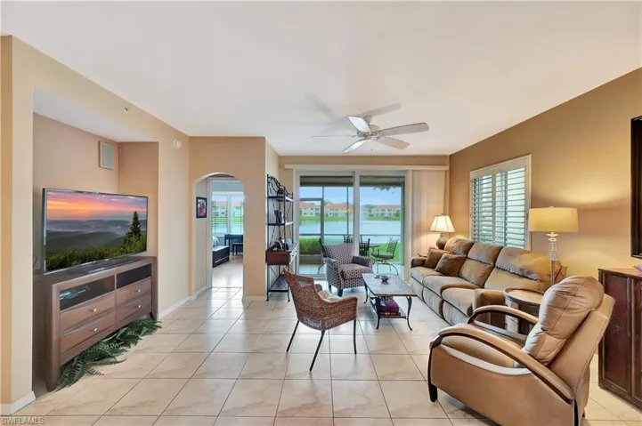 Living room featuring a water view, light tile patterned flooring, and ceiling fan