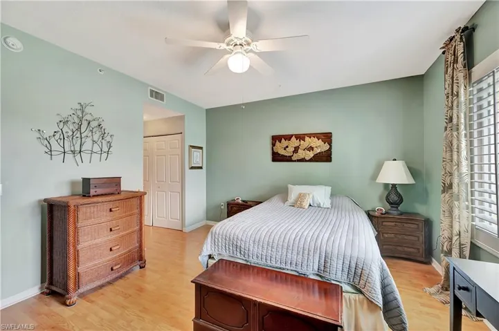 Bedroom featuring a closet, light wood-type flooring, multiple windows, and ceiling fan