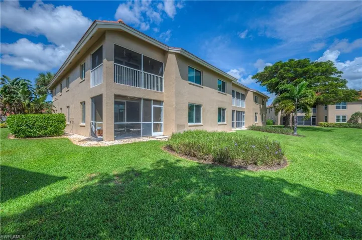 Rear view of house featuring a lawn and a sunroom