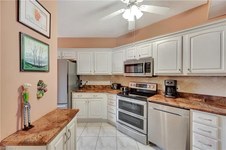Kitchen featuring decorative backsplash, stone counters, stainless steel appliances, and white cabinets