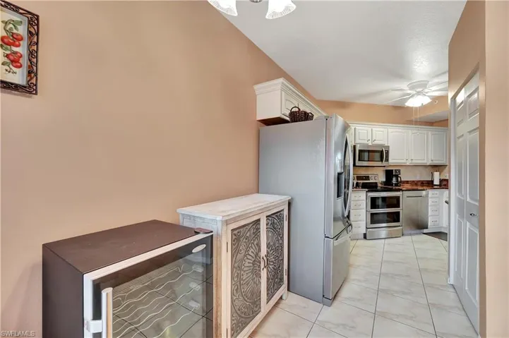 Kitchen with appliances with stainless steel finishes, ceiling fan, wine cooler, and white cabinets