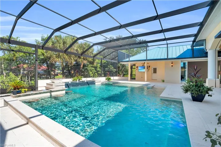 View of pool with glass enclosure, a jacuzzi, and a patio