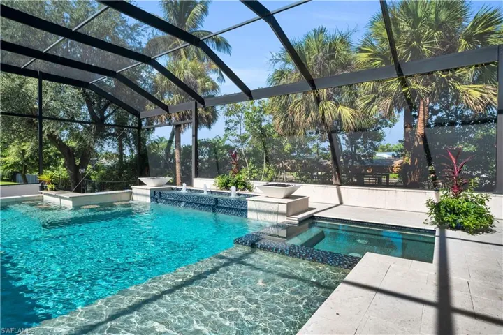 View of swimming pool with pool water feature, a patio, glass enclosure, and an in ground hot tub