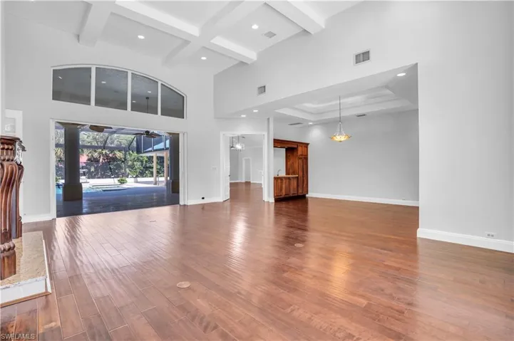 Unfurnished living room with coffered ceiling, a towering ceiling, beamed ceiling, and dark hardwood / wood-style flooring