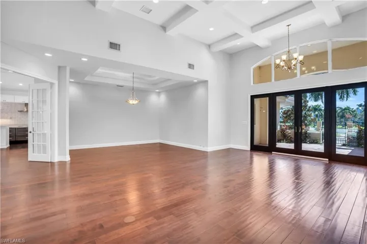 Unfurnished living room featuring coffered ceiling, dark hardwood / wood-style flooring, beam ceiling, french doors, and a high ceiling