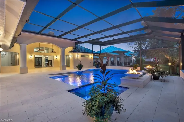 View of pool with a lanai, a patio area, a fire pit, and ceiling fan