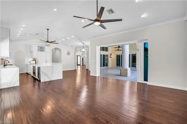 Living room with ceiling fan, dark hardwood / wood-style floors, sink, and vaulted ceiling