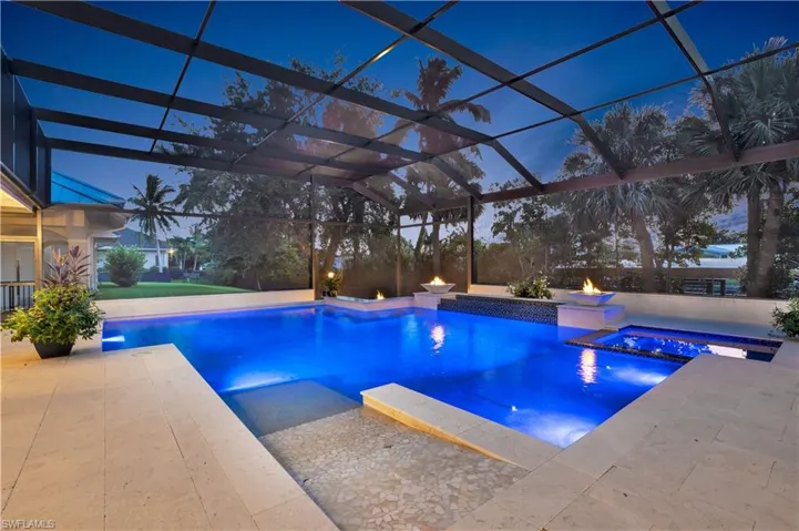 View of pool featuring a patio area, glass enclosure, and an in ground hot tub