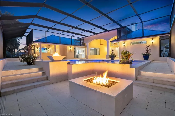 Patio terrace at dusk with a fire pit and glass enclosure