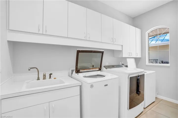 Laundry area featuring cabinets, washer and clothes dryer, sink, and light tile patterned floors