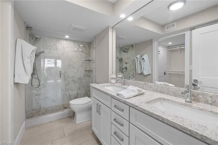 Spacious bathroom featuring a dual vanity with undermount sinks, granite countertops, and white shaker-style cabinetry