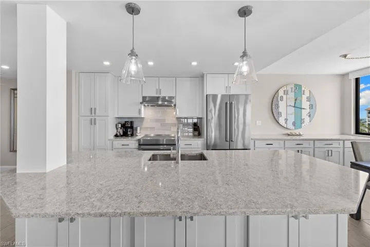 Spacious kitchen island featuring a light-toned countertop with integrated sink and modern fixtures
