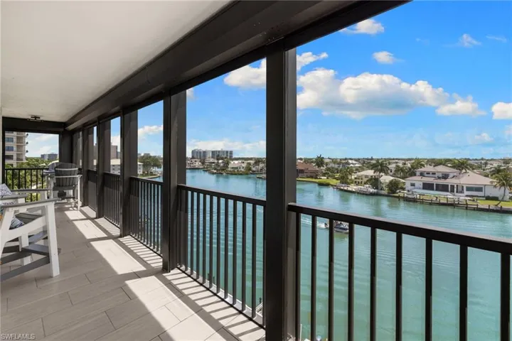 Expansive balcony featuring a water view, black metal railings, and light-toned tile flooring