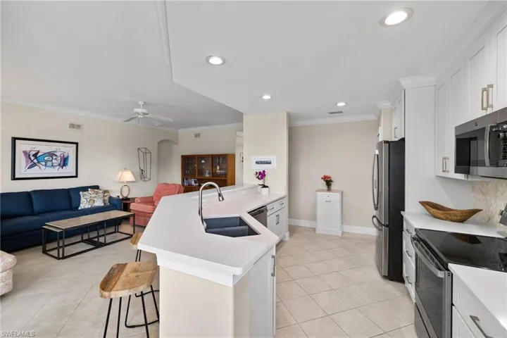 Kitchen featuring a breakfast bar, ornamental molding, a sink, open floor plan, and appliances with stainless steel finishes