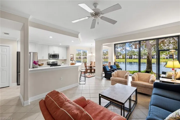 Living room with visible vents, a water view, light tile patterned flooring, and crown molding