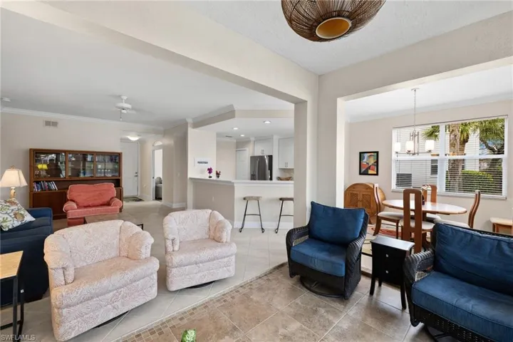 Living area with visible vents, an inviting chandelier, crown molding, light tile patterned floors, and baseboards