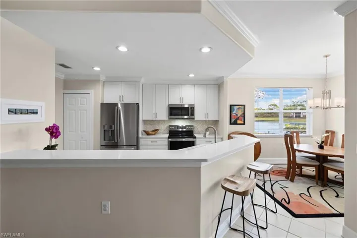 Kitchen featuring tasteful backsplash, a breakfast bar, light countertops, ornamental molding, and stainless steel appliances