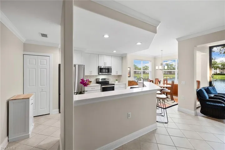 Kitchen with a sink, crown molding, light tile patterned floors, and stainless steel appliances