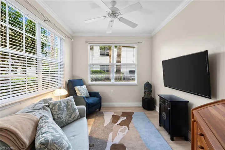 Living room featuring crown molding, light wood-style flooring, a ceiling fan, and baseboards