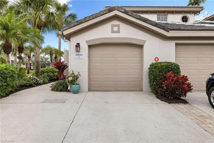 View of front facade with stucco siding, a tiled roof, concrete driveway, and a garage