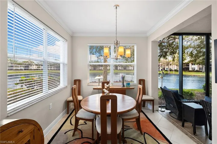Dining room with light tile patterned floors, baseboards, an inviting chandelier, ornamental molding, and a water view