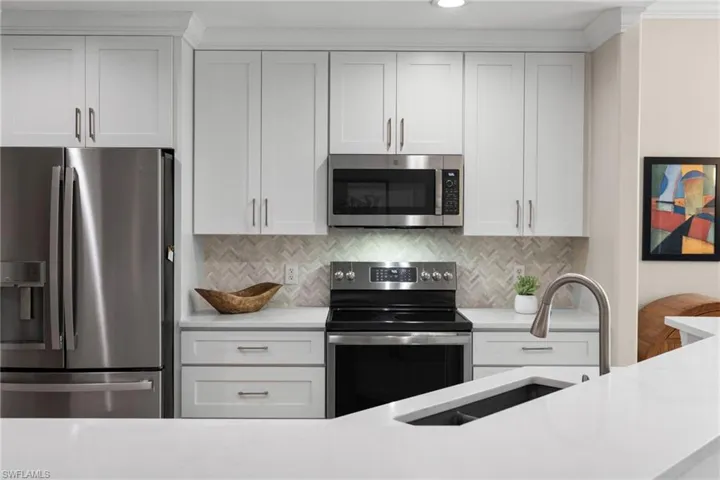 Kitchen featuring a sink, stainless steel appliances, light countertops, white cabinets, and backsplash