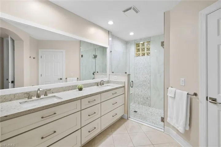 Full bathroom with a shower stall, visible vents, tile patterned floors, and a sink