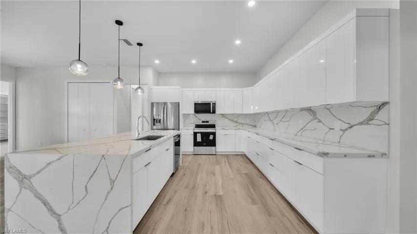 Kitchen featuring white cabinetry, light stone countertops, pendant lighting, tasteful backsplash, and recessed lighting