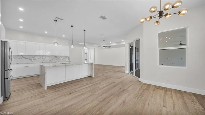 Kitchen featuring white cabinetry, modern cabinets, open floor plan, hanging light fixtures, and recessed lighting