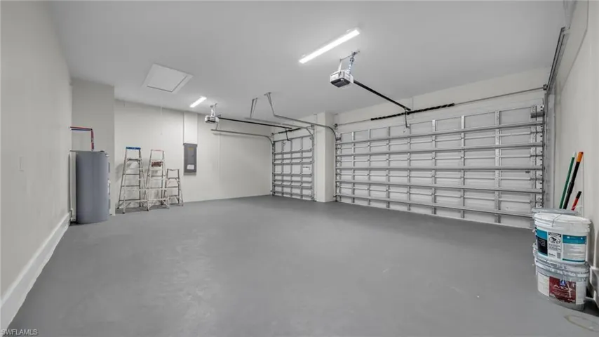 Garage featuring electric water heater, electric panel, and a garage door opener