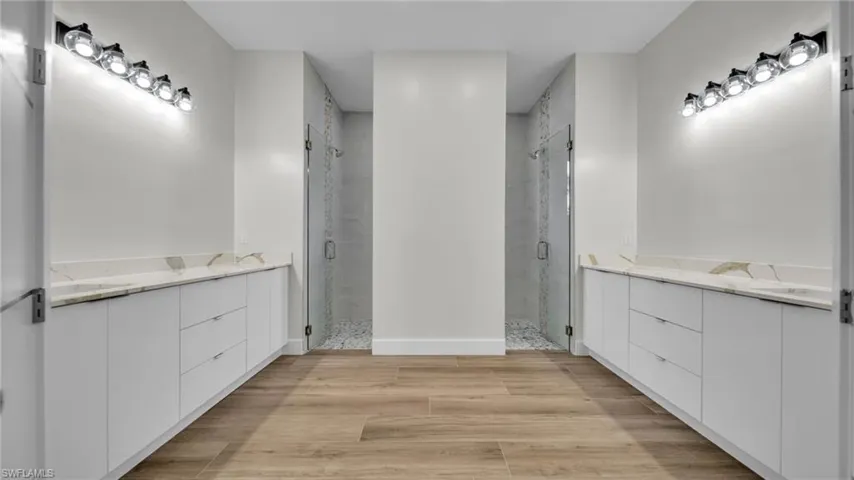 Bathroom with a shower stall, two vanities, and light wood finished floors